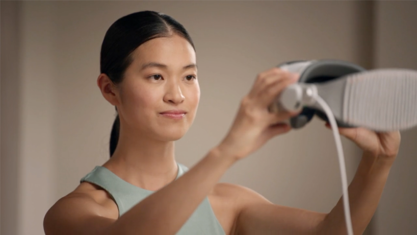 Una persona sostiene un Apple Vision Pro frente a su cara a la altura de los ojos para capturar la Persona digital.