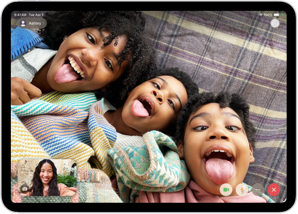 ஒரு FaceTime வீடியோ அழைப்பு செயலில் உள்ளது. கீழ் இடதுபுறத்தில் அதில் பங்கேற்கும் ஒருவர் காட்டப்பட்டுள்ளார். மீதமுள்ள திரையில் மற்ற மூன்று பங்கேற்பாளர்களின் படம் காட்டப்பட்டுள்ளது. கீழே வலதுபுறத்தில் “கேமரா”, “மைக்ரோஃபோன்”, “மேலும்”, “அழைப்பை முடி” ஆகிய பட்டன்கள் காட்டப்பட்டுள்ளன.